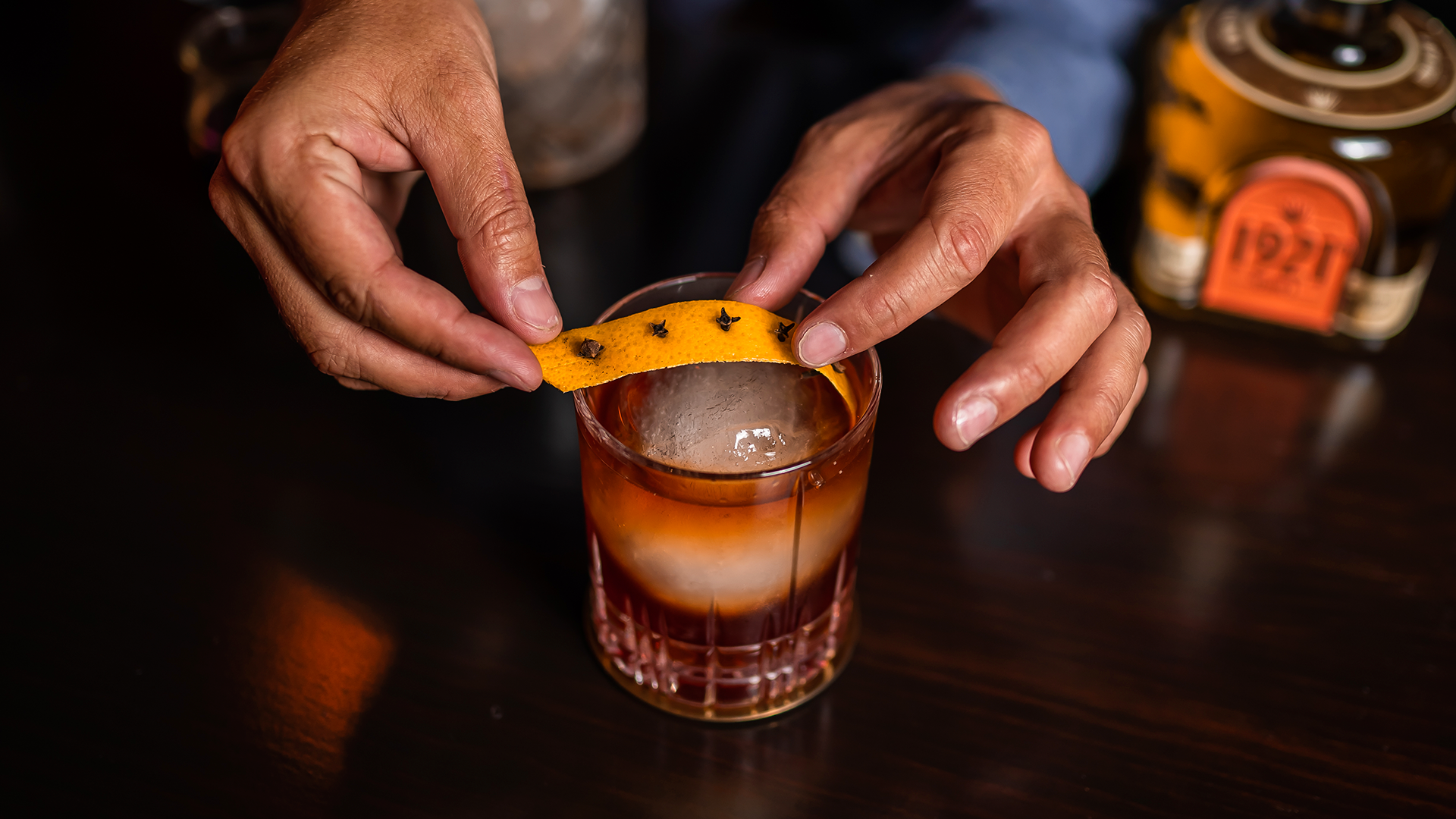 Expressing the orange peel over the cocktail
